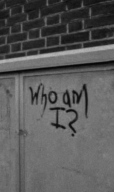 graffiti on the side of a building that says who am i?