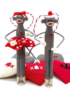 two sock monkey dolls standing next to each other on top of pillows and hearts in front of them