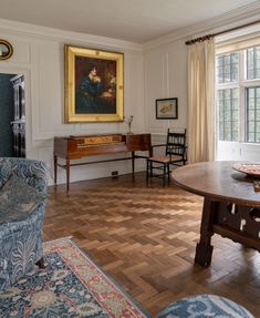 a living room filled with furniture and a painting hanging on the wall above a wooden table