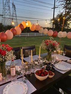 the table is set with plates, bowls and candles for an outdoor dinner party in the evening