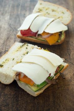 two slices of bread with different types of food on them sitting on a wooden surface