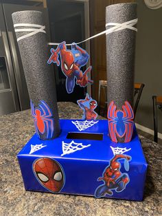 a blue box with spiderman stickers on it and two tall vases in the background