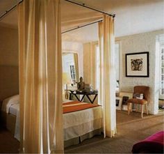 a bedroom with four poster bed and white drapes