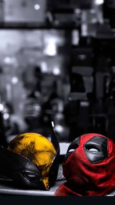 two masks are sitting on top of a table in front of other items, one yellow and the other red