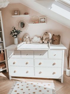 a baby's room with a dresser, crib and stuffed animals on it