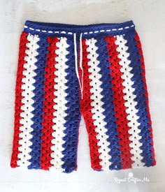 a red, white and blue crocheted shorts is laying on top of a bed