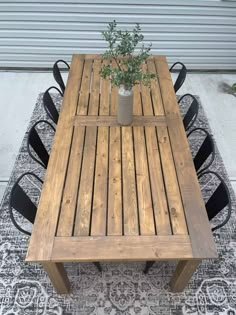 a wooden table sitting on top of a rug next to a metal chair and potted plant