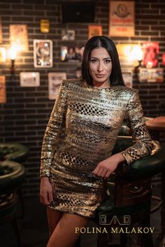 a woman posing for a photo in a gold sequinned dress with her hands on her hips