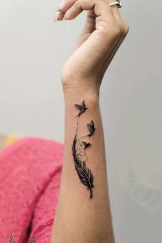 a woman's arm with a black feather tattoo on it