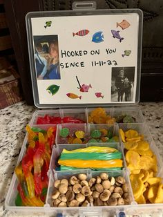 a plastic container filled with different types of snacks and nuts next to a sign that says hooked on you since 11 / 10a