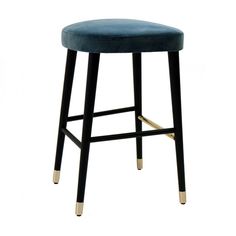 an upholstered stool with gold legs and a blue velvet seat pad on the back