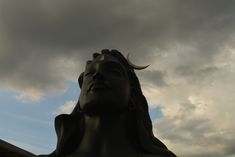 there is a statue with horns on it's head and clouds in the background