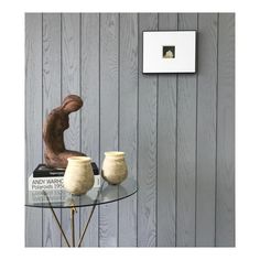 a glass table topped with two vases next to a wall mounted art piece on a wooden paneled wall