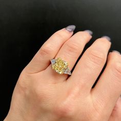 a woman's hand with a yellow diamond ring