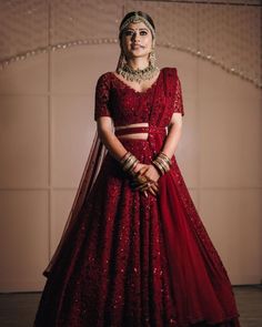 a woman in a red lehenga standing with her hands on her hips and looking at the camera