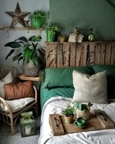 a bed with green sheets and pillows in a room filled with potted plants on top of it