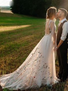 a bride and groom kissing in the grass