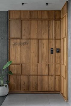 an empty room with a plant in the corner and wooden paneling on the wall