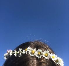 a woman with flowers in her hair looking up at the sky on a sunny day