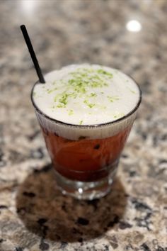 a close up of a drink in a glass on a table with a black straw sticking out of it