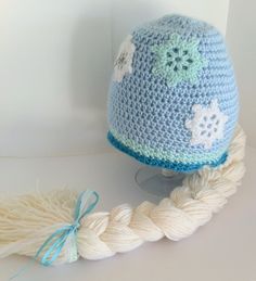 a crocheted blue hat with flowers on it next to a skeine of yarn