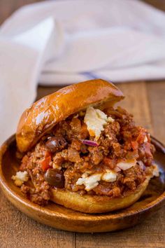 a sloppy joe sandwich sitting on top of a wooden plate