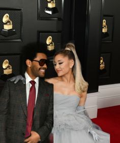 a man and woman standing next to each other on the red carpet at an awards event