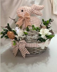 a basket filled with flowers and a stuffed bunny sitting on top of it's side