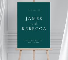 an easel with a wedding sign on it in front of a white wall and curtains