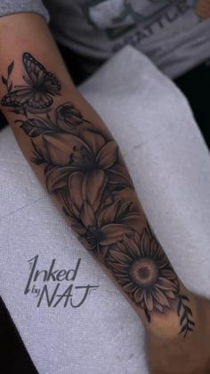 a woman's arm with black and white tattoos on it, flowers and butterflies