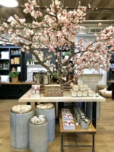 a table with jars and flowers on it in a room filled with bookshelves