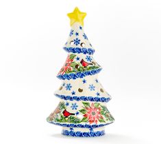 a ceramic christmas tree with birds and flowers painted on it's sides, sitting in front of a white background