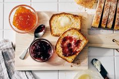 bread with jams and butter on a cutting board next to some slices of bread