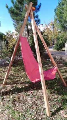 a pink hammock hanging from a wooden frame