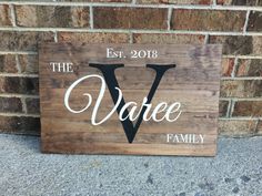 a wooden sign that says the vare family on it, in front of a brick wall