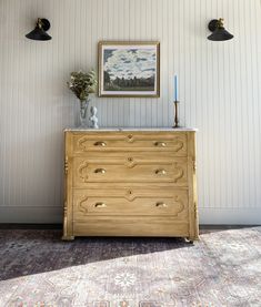 a wooden dresser sitting next to two black lights and a painting on the wall above it