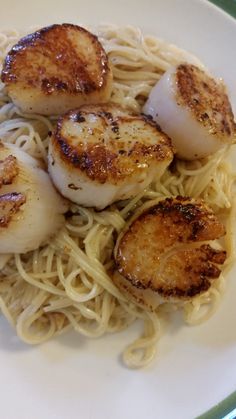 some scallops and noodles on a white plate