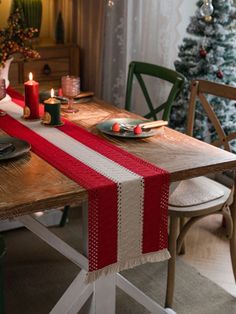 a christmas table setting with candles, plates and napkins on the dining room table