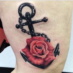 a rose with an anchor tattoo on the thigh