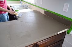 a man standing in front of a kitchen counter with a tile on top of it