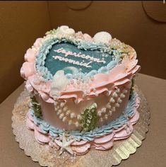 a heart shaped cake decorated with pearls and sea shells on top of a cardboard box