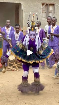 a group of people standing around each other in front of a building and wearing purple outfits