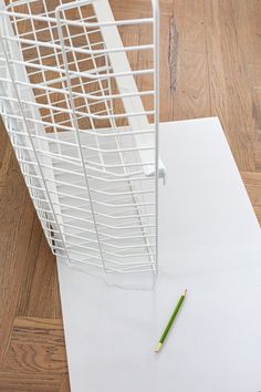 a pencil laying on top of a piece of white paper next to a wire basket