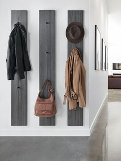 a coat rack with three coats hanging on it and two purses in the foreground