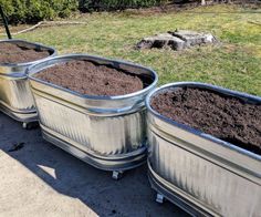 three metal containers filled with dirt sitting on top of a sidewalk