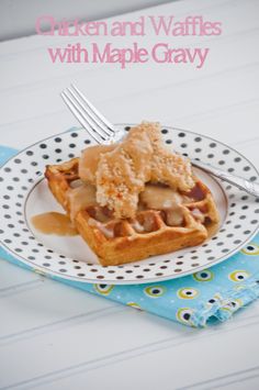 chicken and waffles with maple gravy on a polka dot plate next to a fork