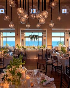 a room filled with lots of tables covered in white clothed tablecloths and centerpieces