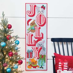 a christmas banner hanging on the wall next to a chair with presents and a tree