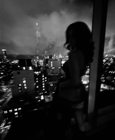 a woman standing on top of a tall building looking out at the cityscape