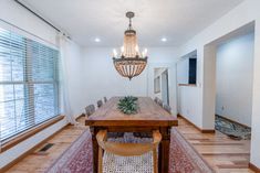 a dining room table and chairs with a chandelier hanging from the ceiling above it